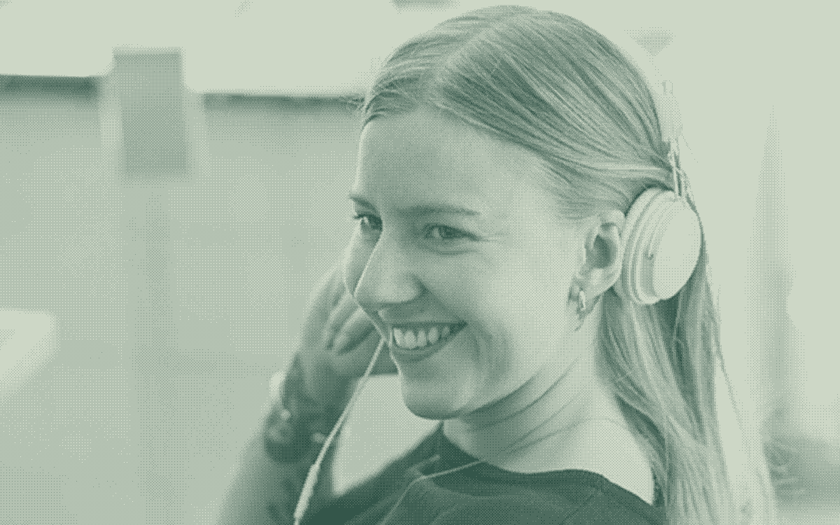 A woman wearing headphones in a bright workspace.